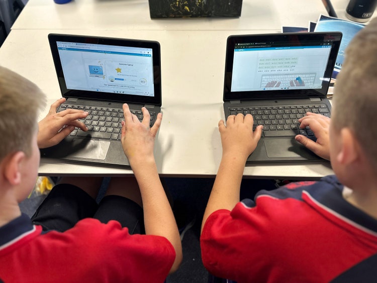 Photo from behind two students working on laprtops.