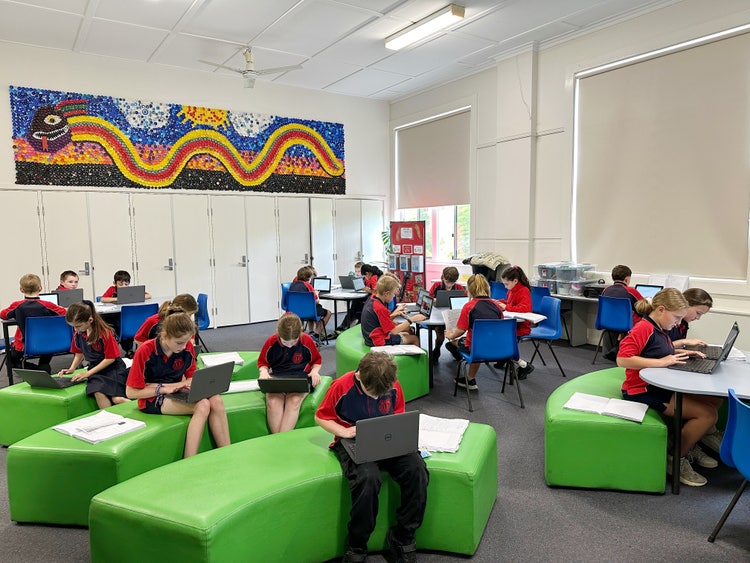 A group of students working on laptops in the technology room.