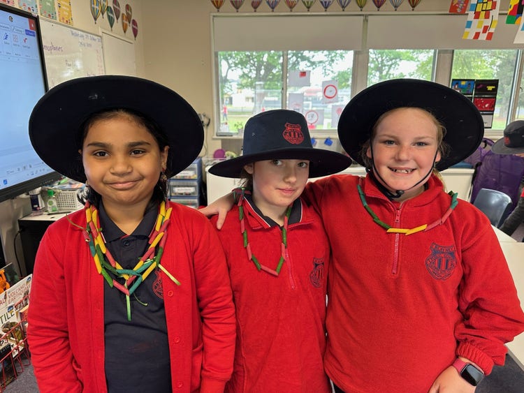 Three students showing their neclaces they made in craft club during lunch time.