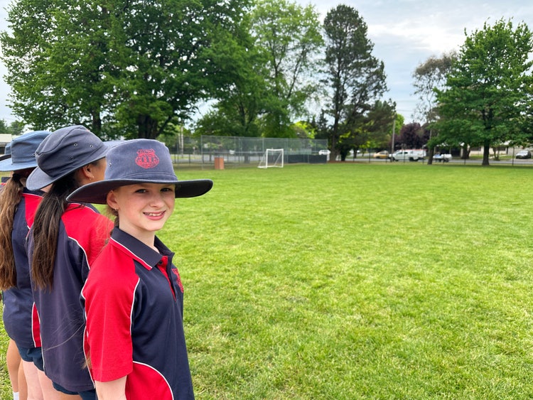 Students standing on the oval with soccer goals in the background.