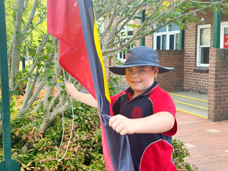 A student raising the Aboriginal Flag.