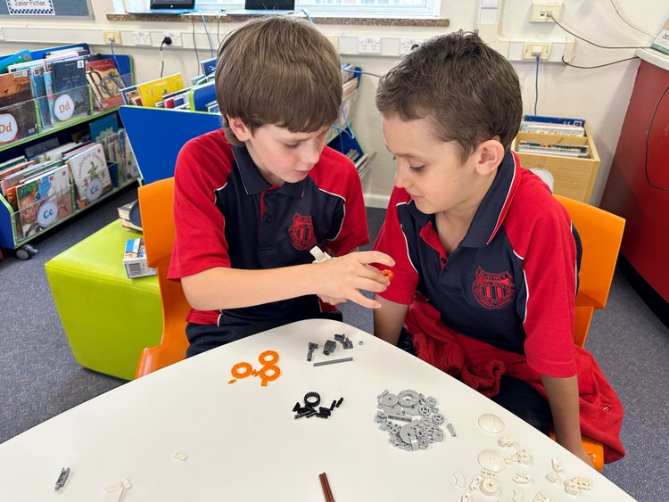 Two students playing with some lego in the library during break time.