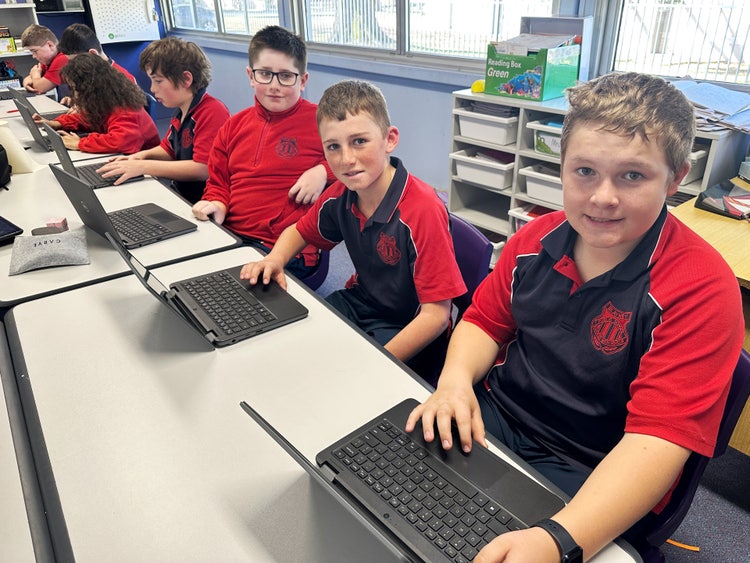 Male students using laptops in the classroom.