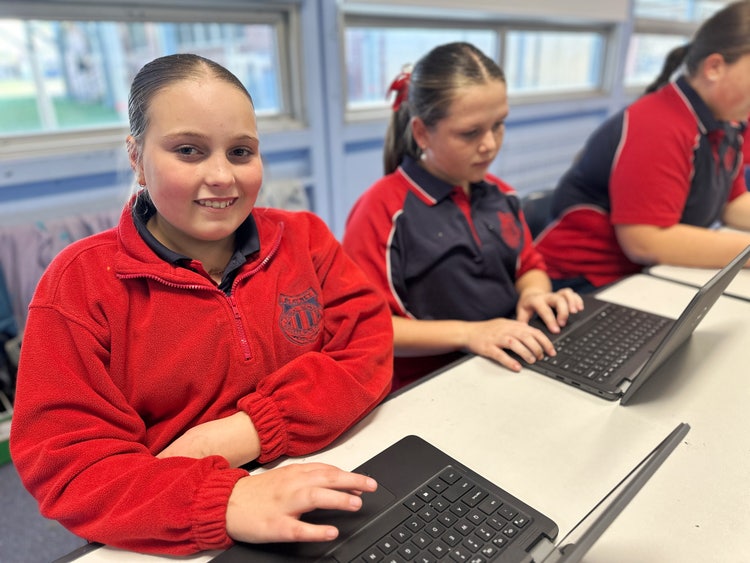 Female students working on laptops in their classroom.
